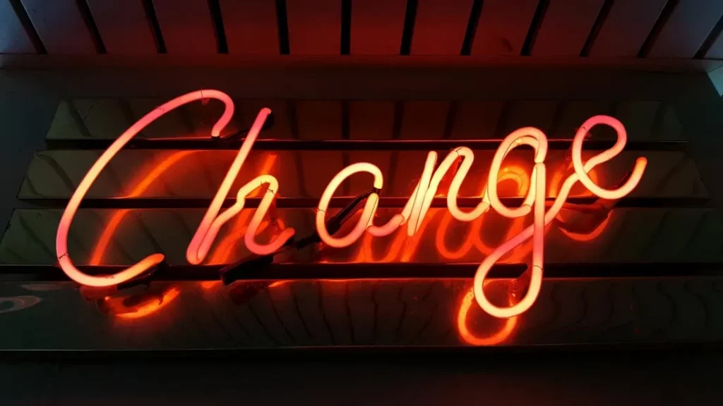 Eine Leuchtschrift in Rot und Gelb mit dem Wort „Change“ vor einer dunklen Wand