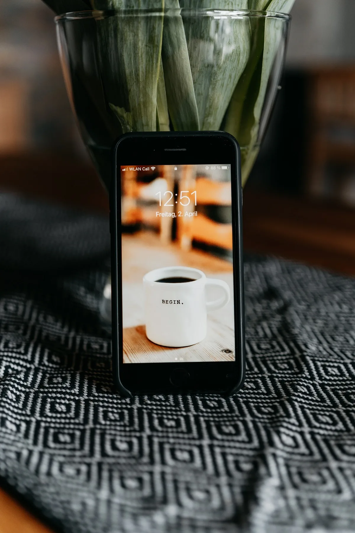 Ein Smartphone lehnt an einer Vase mit Tulpen und zeigt das Foto einer Kaffeetasse